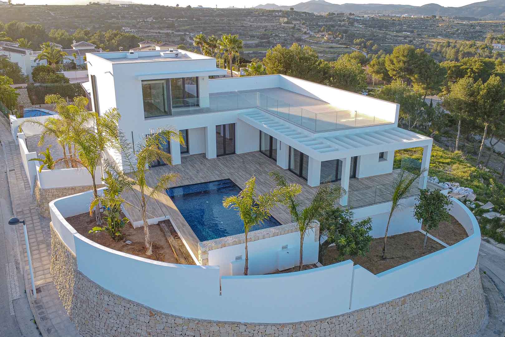 Aerial view of modern villa with blue pool and white walls with stone details in Benimeit, Moraira.