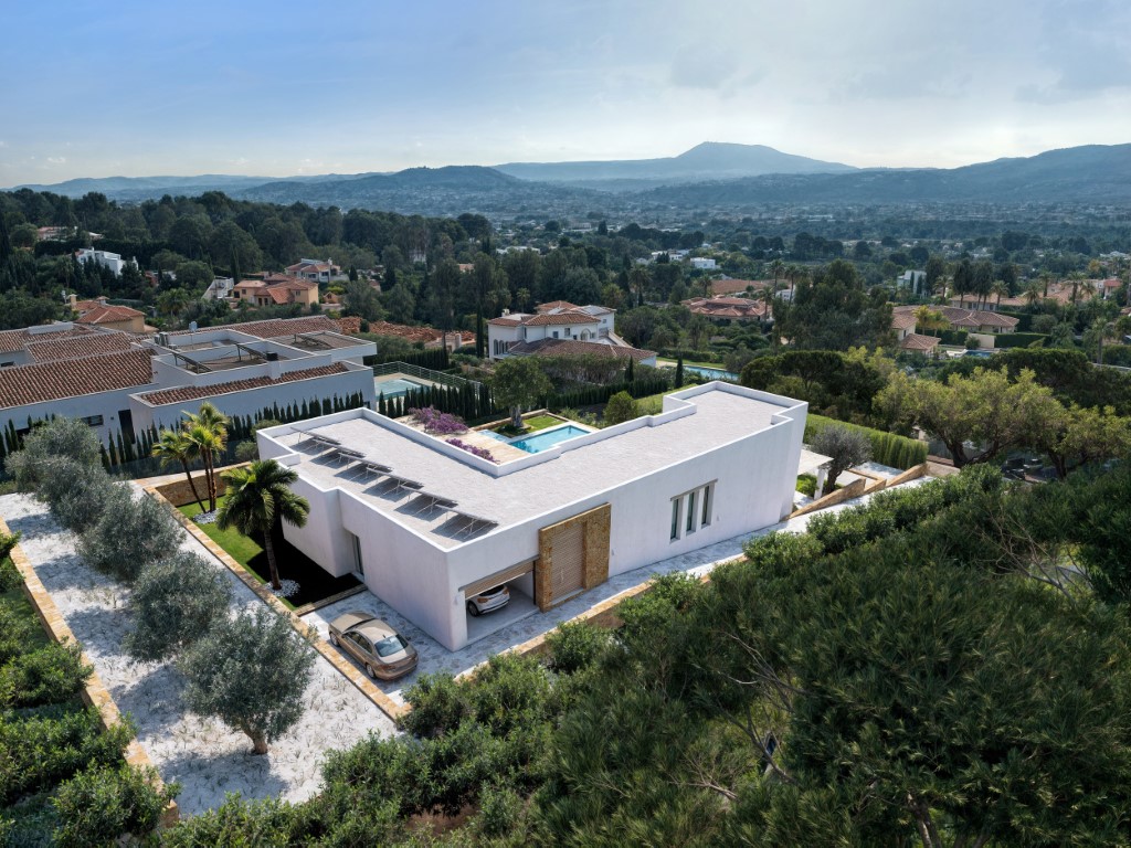 Aerial perspective of the modern L-shaped villa featuring rooftop solar panels, integrated garage, and landscaped gardens with valley views.