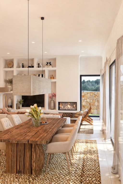 Bright dining area featuring a rustic wood table, natural fiber rug, and built-in wall shelving.