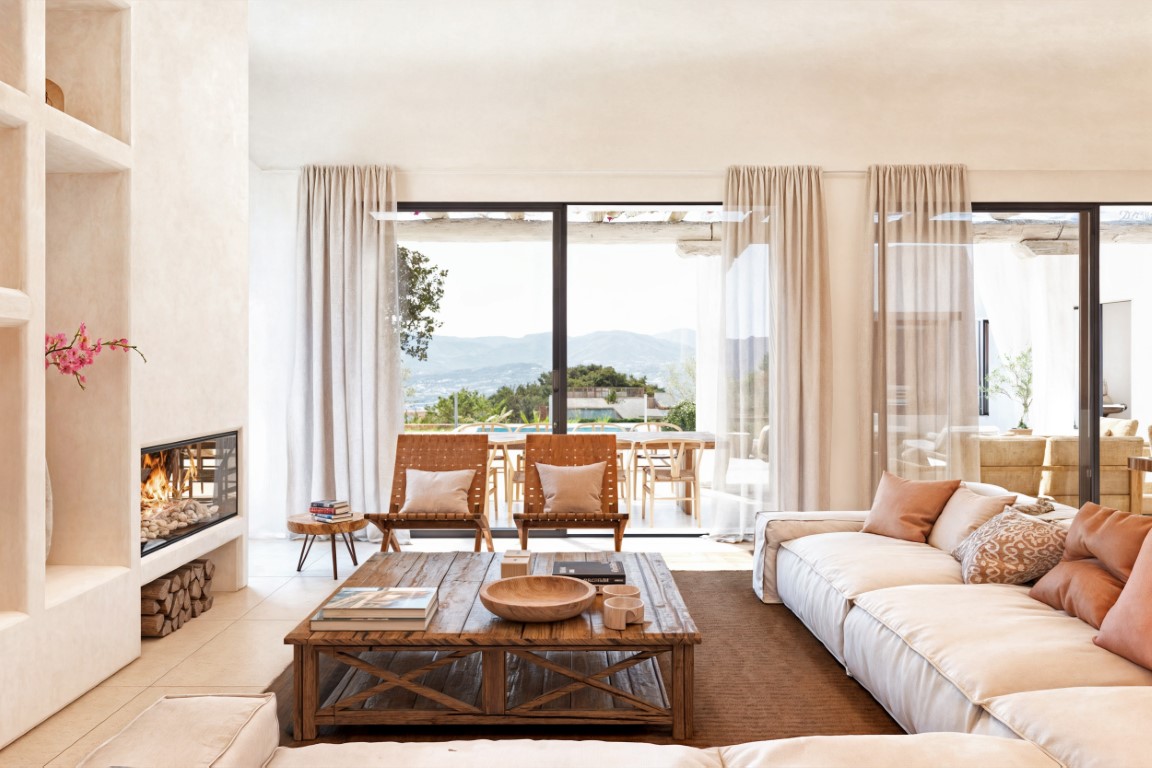 Bright living room featuring a built-in fireplace, rustic wooden coffee table, and large sliding doors opening to a terrace with expansive valley views.
