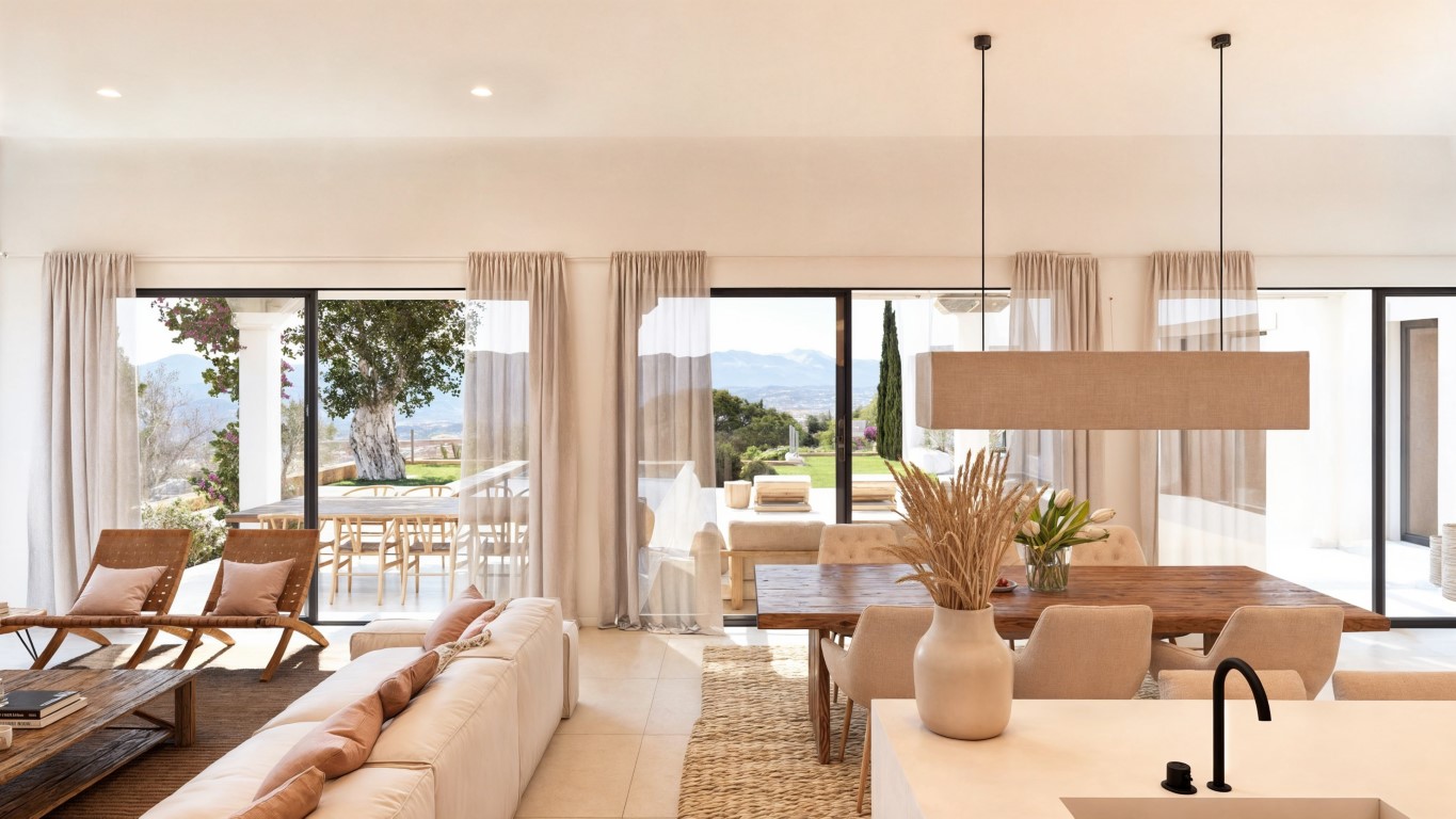 Open-plan living and dining area featuring large sliding glass doors, a solid wood table, and panoramic mountain views across the sunny terrace.
