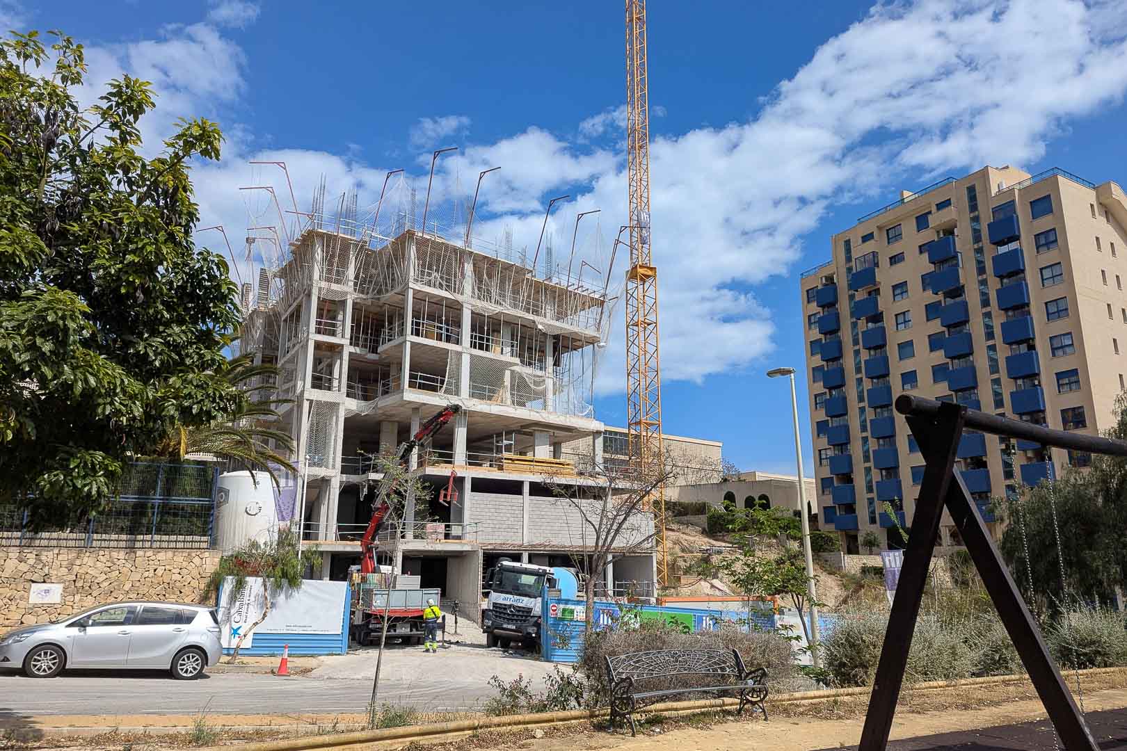 Current construction progress in Calpe, featuring the reinforced concrete structure, safety netting, and onsite machinery under a clear sky.