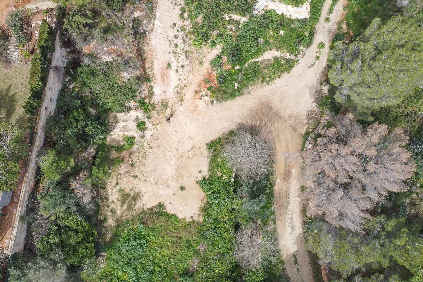 Aerial view of the building plot in La Corona, featuring natural Mediterranean terrain and access paths ready for a custom-built villa project.
