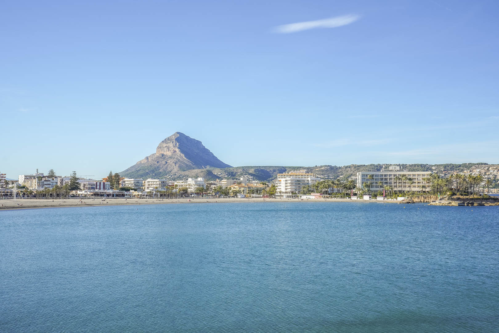 Panoramic view of Jávea bay featuring the iconic Montgó mountain, showcasing the coastal landscape and the Mediterranean Sea under a clear blue sky.