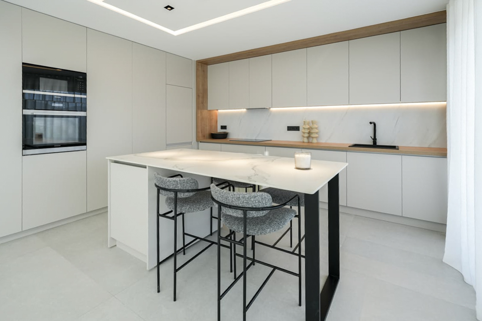 Kitchen detail featuring a marble island and gray stools. Modern, functional design.