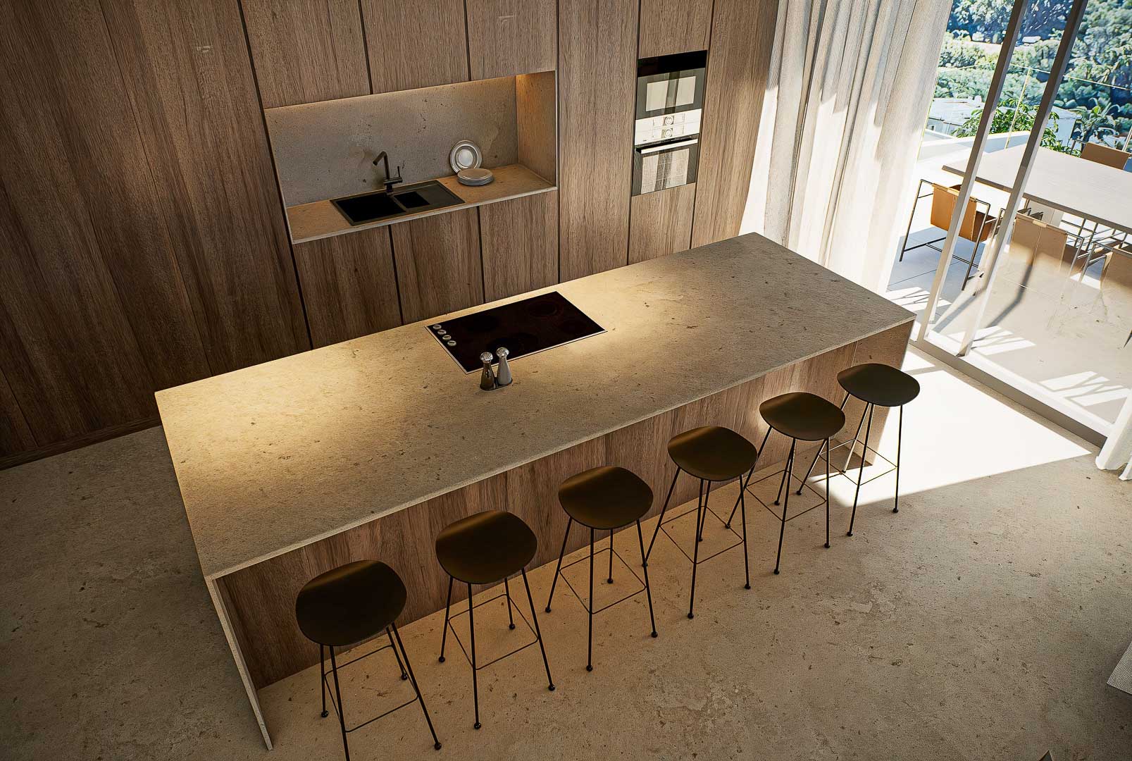 Designer kitchen featuring a large stone island with integrated cooktop, minimalist bar stools, and full-height wood cabinetry. Natural light flows from the terrace glass doors.
