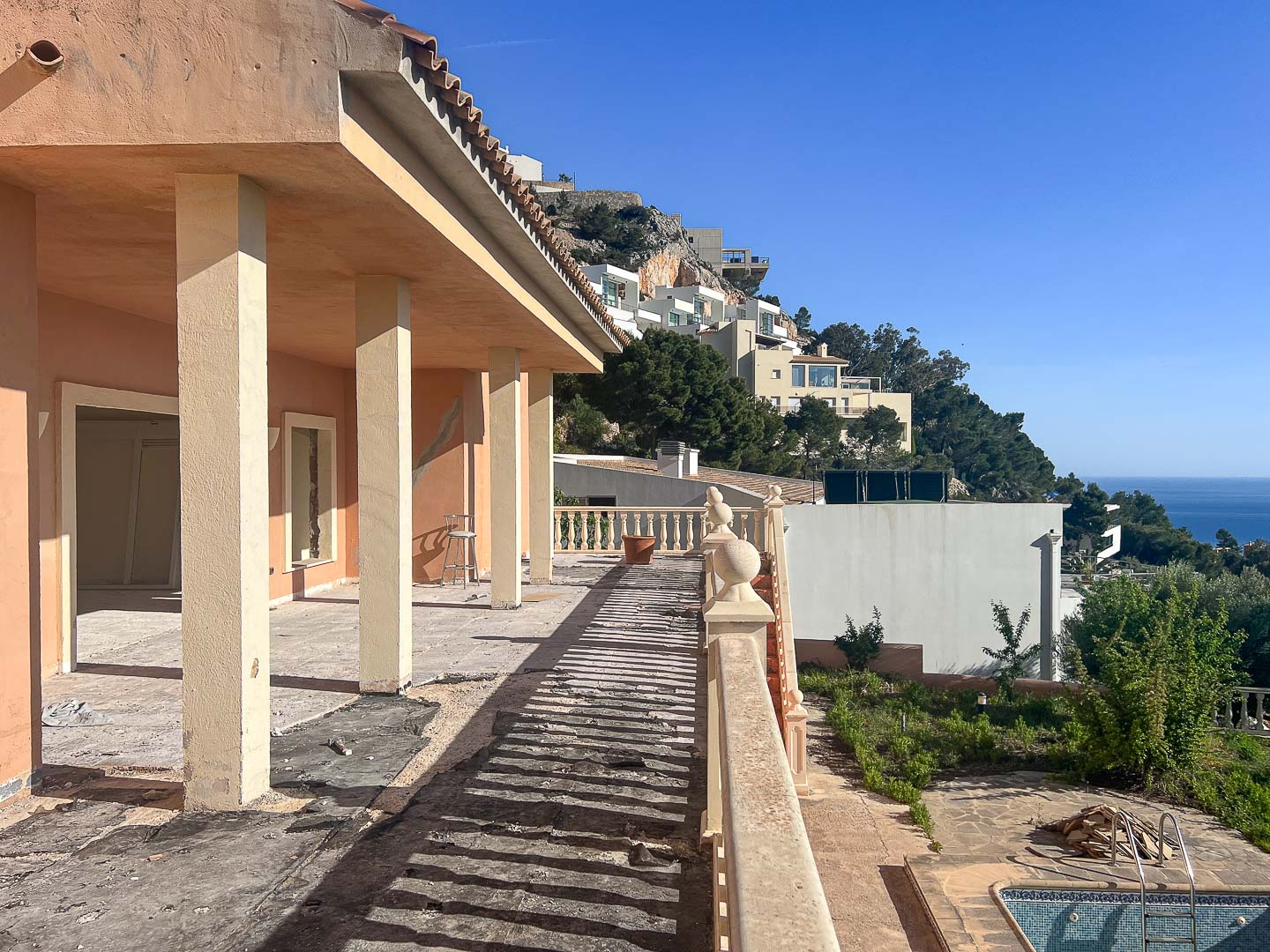Exterior terrace under renovation featuring structural columns, a classic balustrade, and panoramic views of the Altea hillside and Mediterranean Sea.