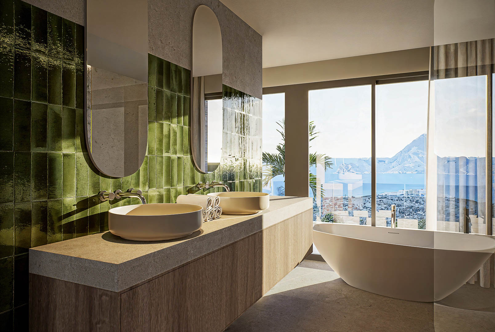 Master bathroom featuring double vessel sinks on a stone vanity, emerald green tiling, and a freestanding tub positioned to enjoy panoramic Mediterranean views.