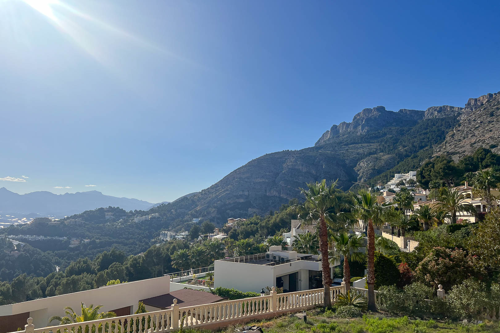 Panoramic view from Altea Hills featuring the Sierra de Bernia mountains, white villas nestled in the hillside, and lush Mediterranean greenery.