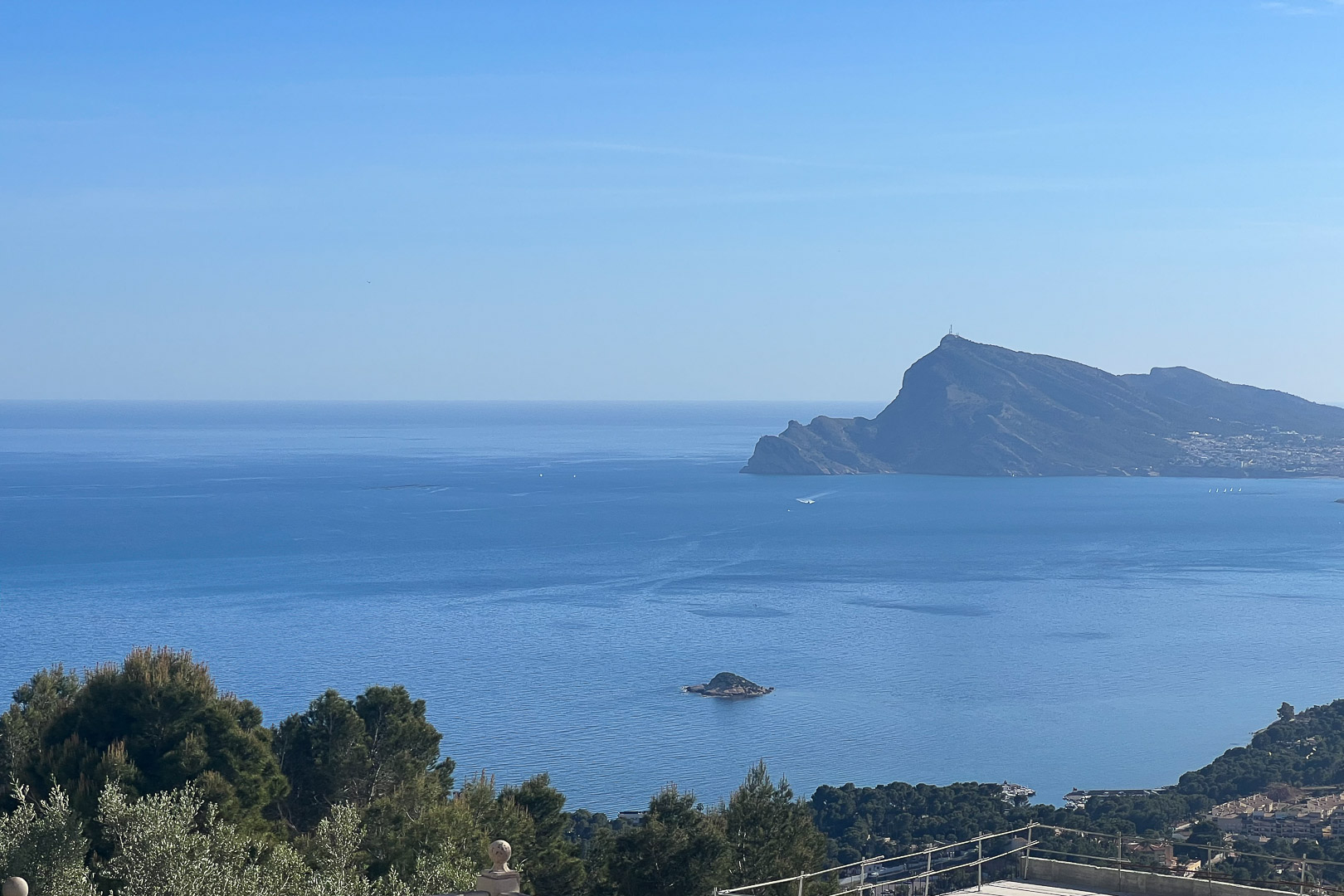 Panoramic views of the Mediterranean Sea and Sierra Helada from Altea Hills. The natural landscape features pine trees and the coastal horizon of the Altea Bay.