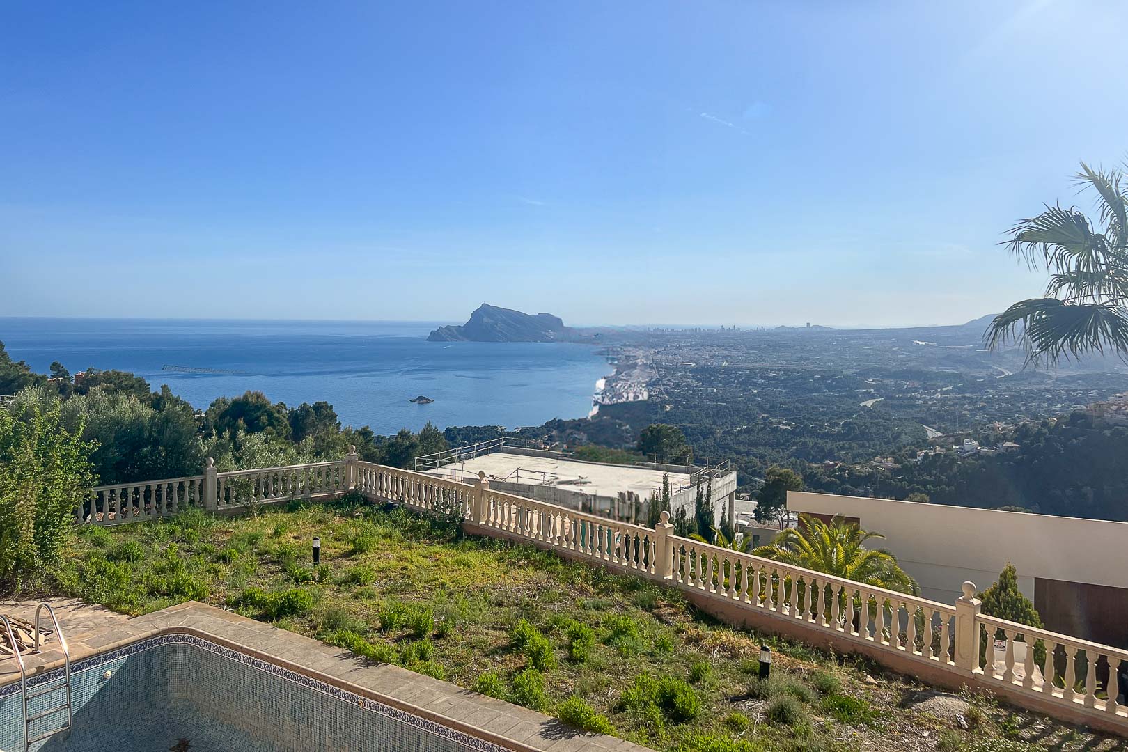 Panoramic views of the Mediterranean Sea and the Peñón de Ifach from the outdoor area with a stone balustrade and garden.