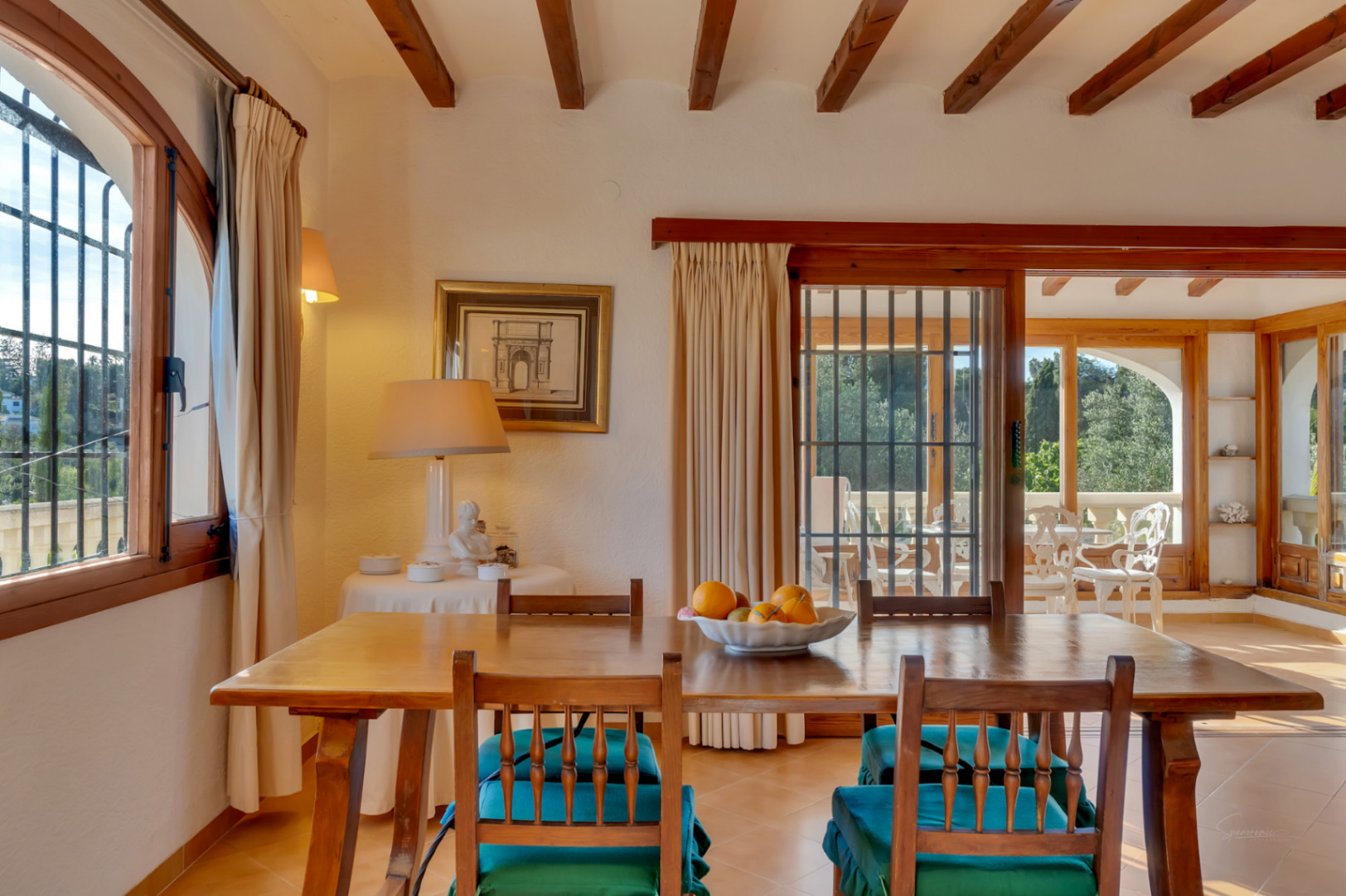Dining area featuring exposed wooden ceiling beams, rustic furniture, and access to the sunroom through sliding wooden doors with natural light.