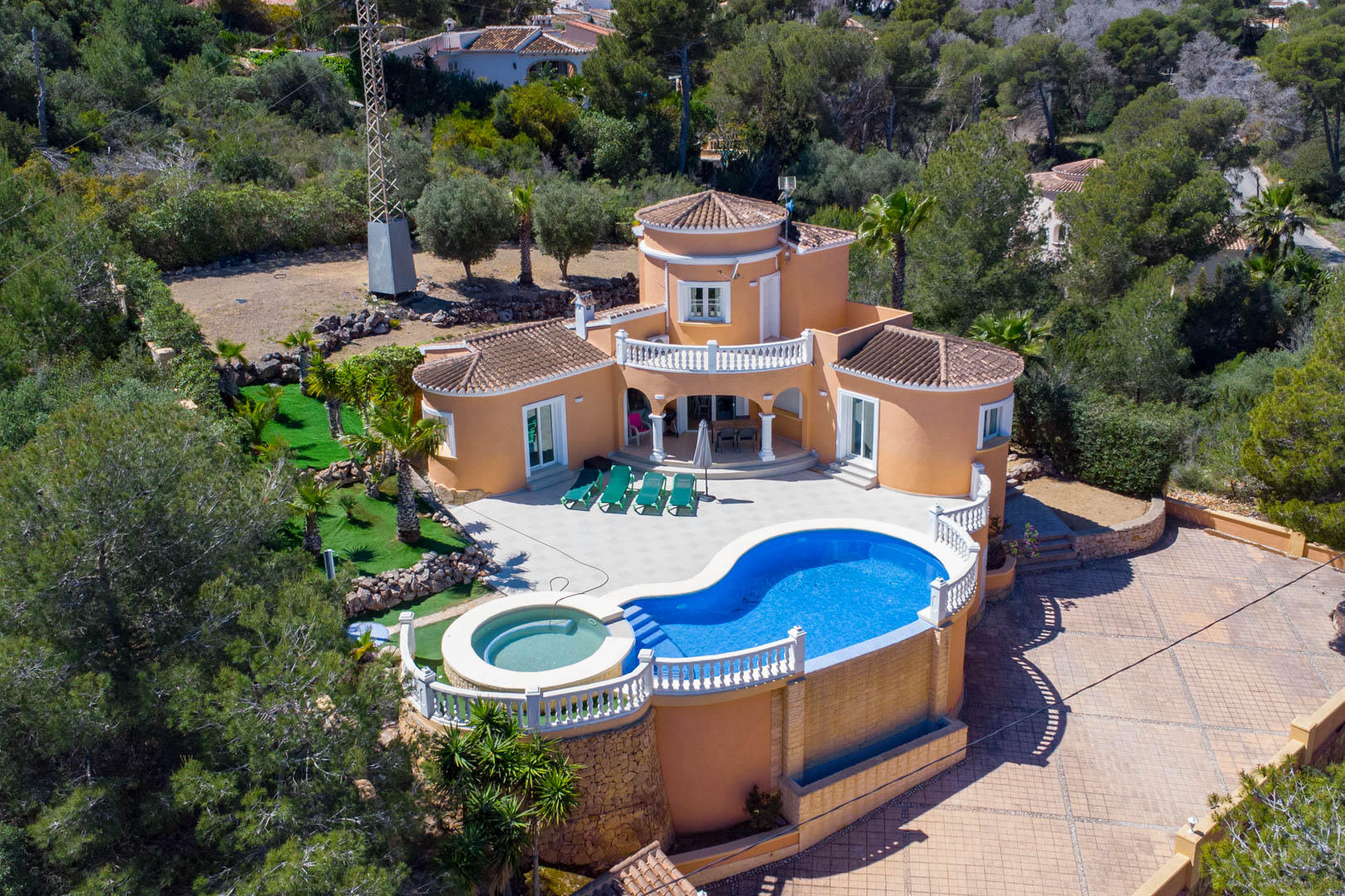 Aerial view of the Mediterranean villa featuring a kidney-shaped pool with integrated jacuzzi, expansive tiled terrace, and traditional terracotta architecture.