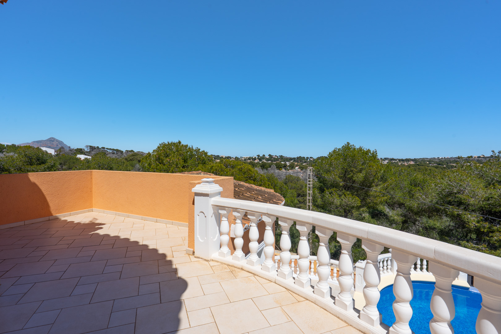 Upper terrace featuring ceramic tiling and a white classic balustrade, overlooking the private swimming pool and the surrounding landscape.