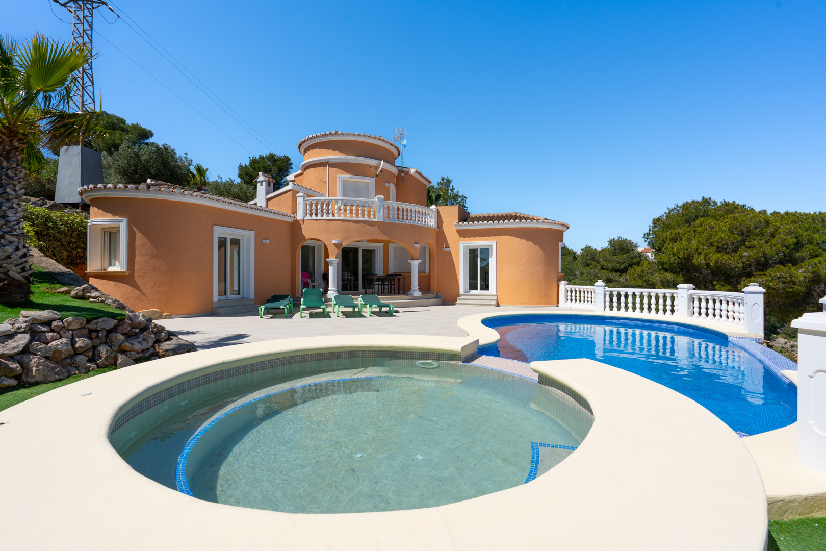 Villa exterior featuring a curved swimming pool with an integrated circular section, spacious sun terrace, and Mediterranean architecture with terracotta walls.