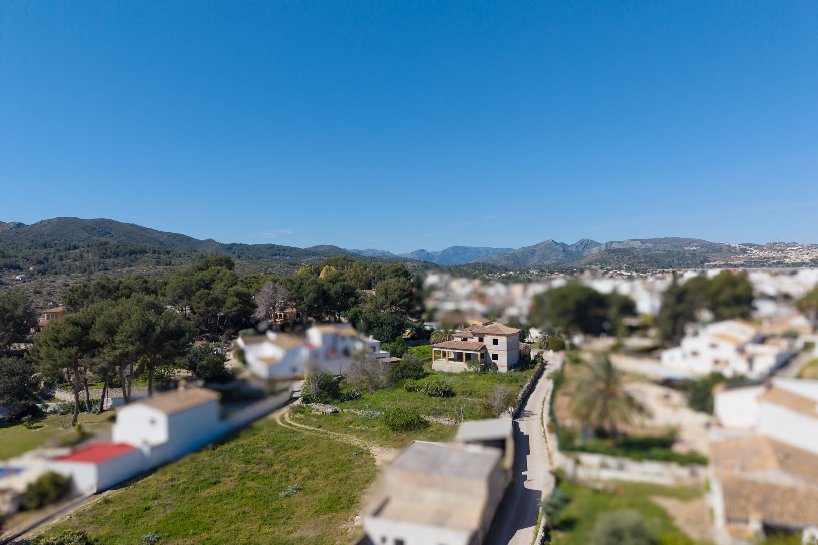 Aerial perspective of the two-story structure under construction, situated on a spacious plot in Gata de Gorgos with scenic mountain views in the background.