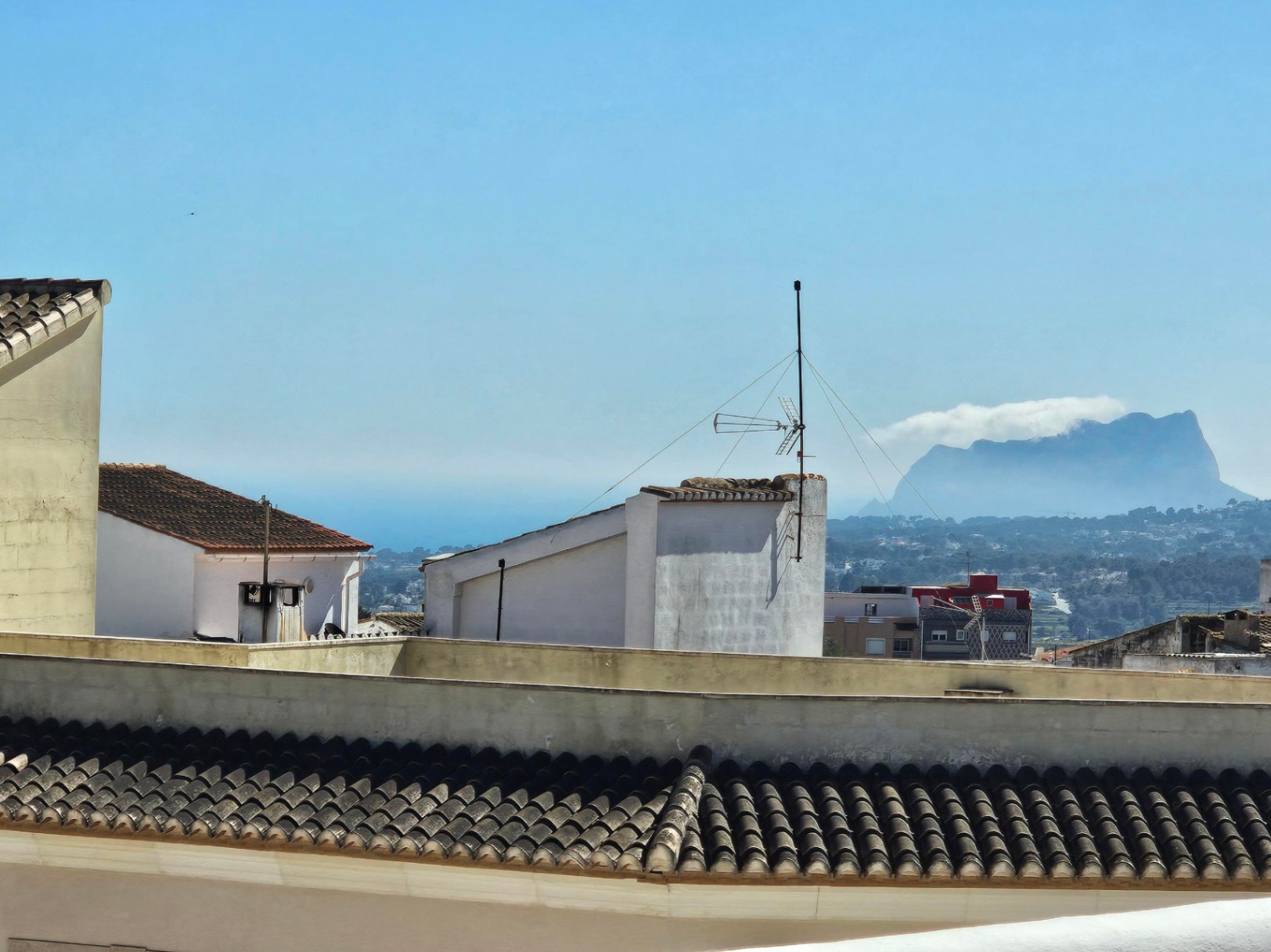 Panoramic views from the upper terrace over the town's rooftops, the valley, and the Mediterranean Sea, featuring the iconic Peñón de Ifach on the horizon.