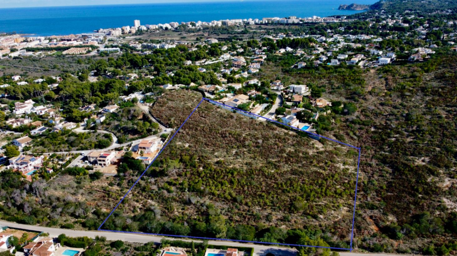 Aerial view of the large plot in Jávea, outlined to show its extent and strategic location with views towards the Mediterranean Sea and the Arenal coast.