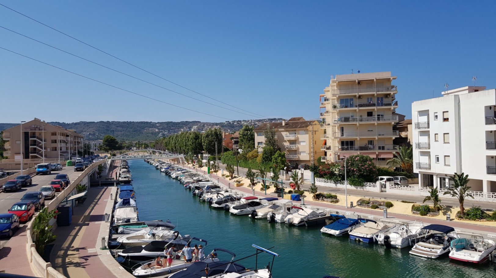 Elevated view from the terrace overlooking the Jávea marina canal, featuring rows of moored leisure boats and surrounding residential buildings.
