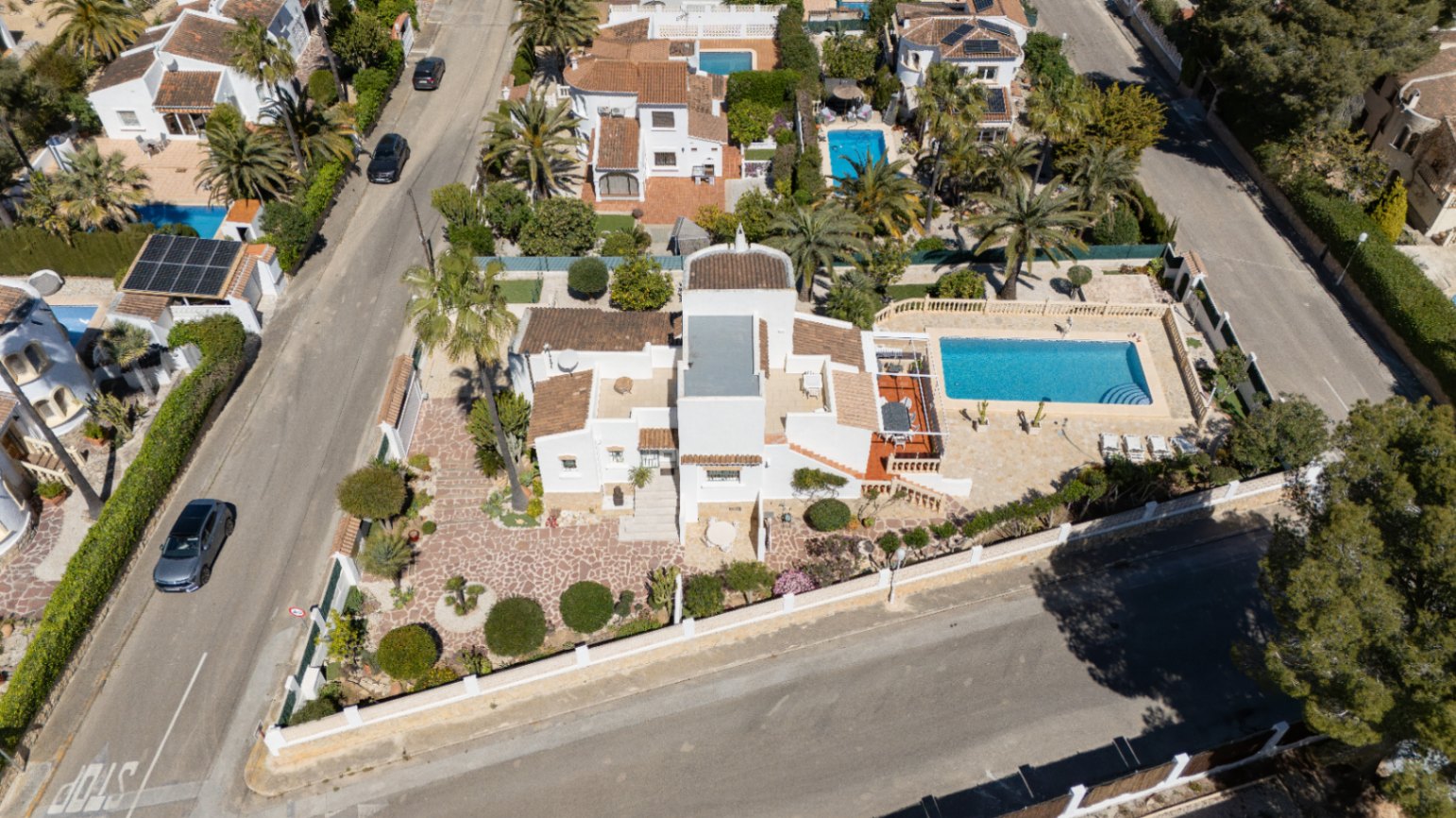 Aerial view of the corner plot featuring a Mediterranean villa with a private pool, stone-paved garden, and multiple sun terraces in Pinosol, Jávea.