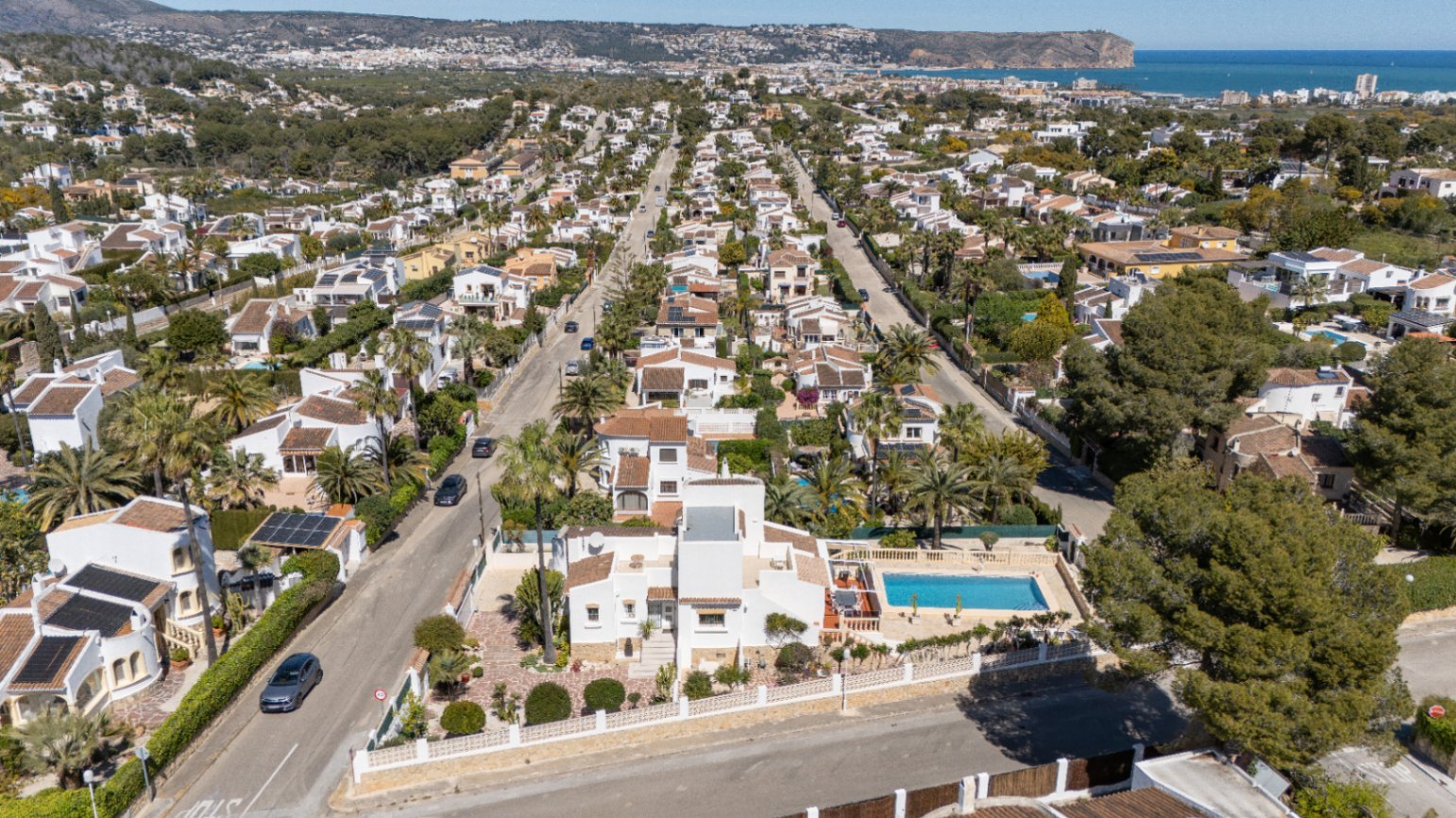 Aerial view showcasing the villa's plot in Pinosol, featuring the private pool and a panoramic backdrop of the Jávea coastline and Mediterranean Sea.