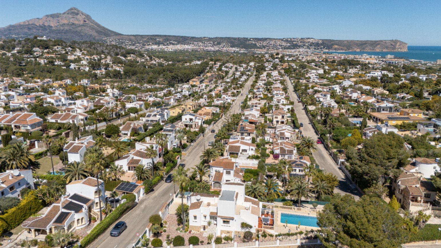 Panoramic aerial view of the Pinosol residential area in Jávea, featuring the Montgó mountain and the Mediterranean coastline in the background.