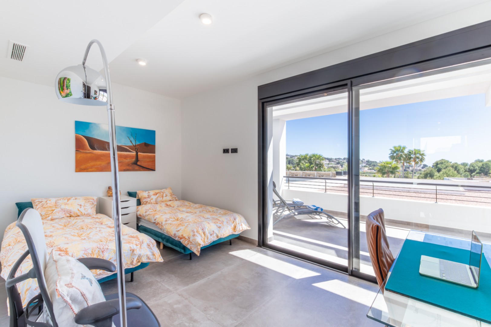Bedroom featuring twin beds, a workspace, and direct access to a private terrace with open views through large sliding glass doors.