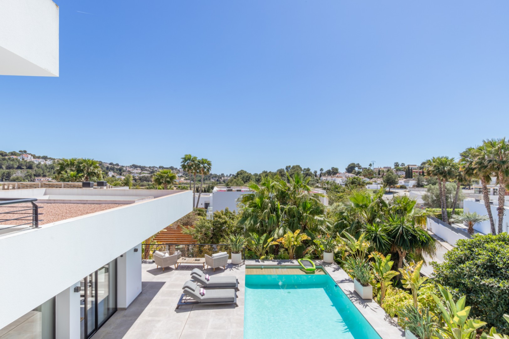 Elevated view of the outdoor area featuring a rectangular pool, porcelain tile terrace, and mature Mediterranean garden with palms for total privacy.