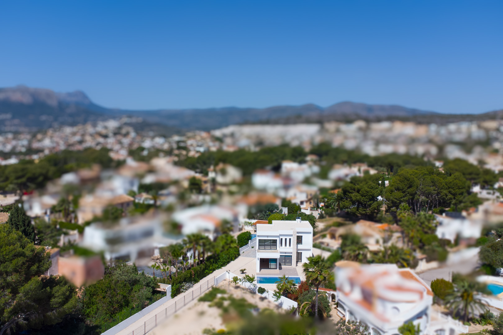 Aerial perspective of the modern two-story villa with a white facade and private pool, showcasing its position within the Mediterranean landscape of Benissa.