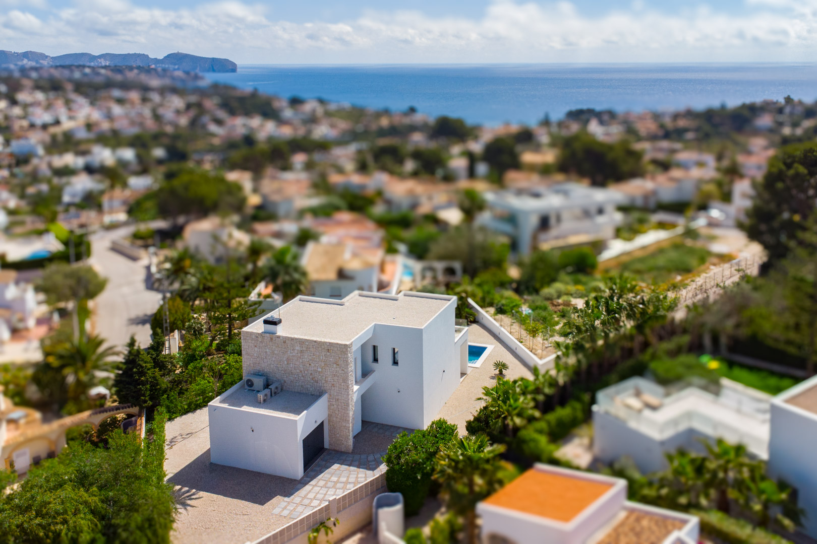 Aerial view of the modern villa featuring natural stone accents and clean white architecture, overlooking the Mediterranean coastline in Benissa.