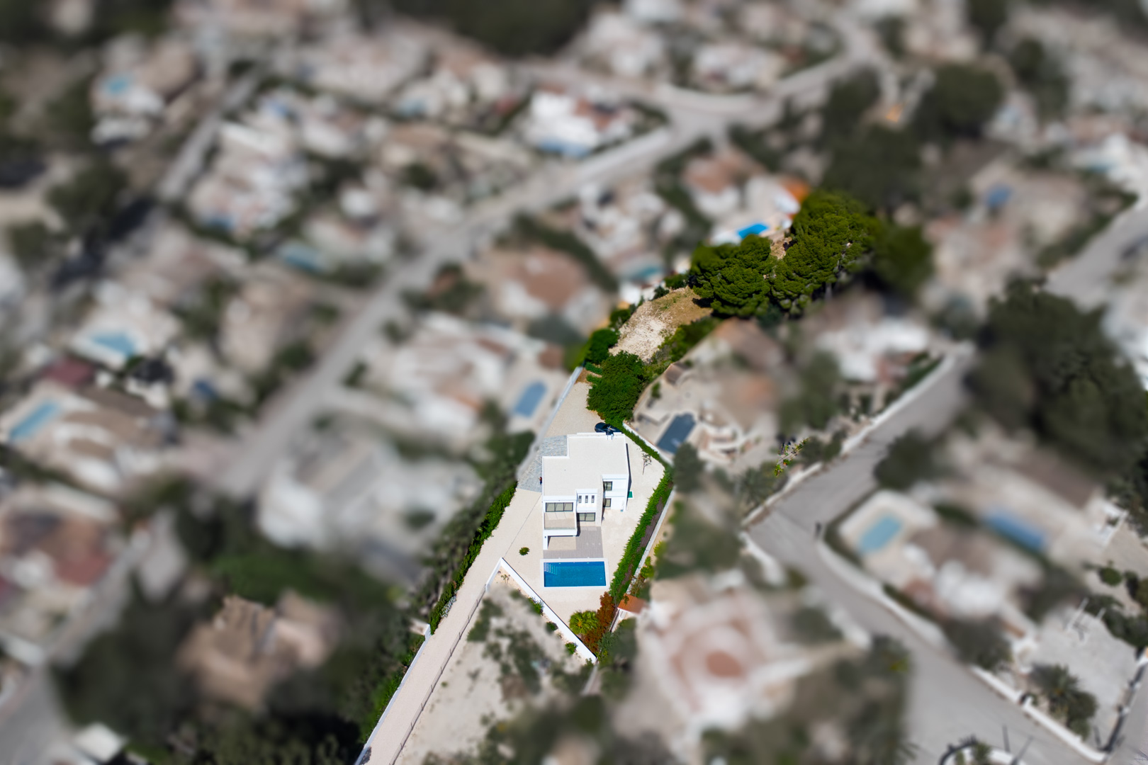 Aerial view of the modern villa situated on an expansive flat plot, featuring a rectangular pool and a large private area for future landscaping in Benissa.