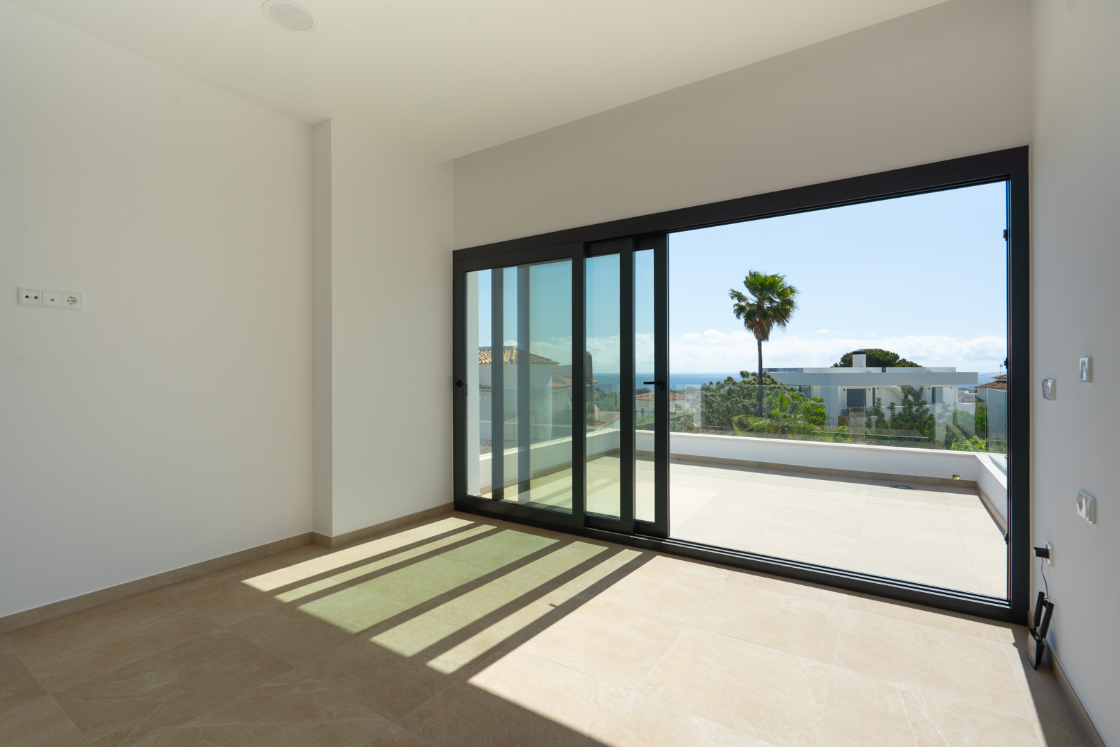 Bright interior featuring porcelain flooring and large sliding glass doors that open onto a private terrace with panoramic Mediterranean Sea views.