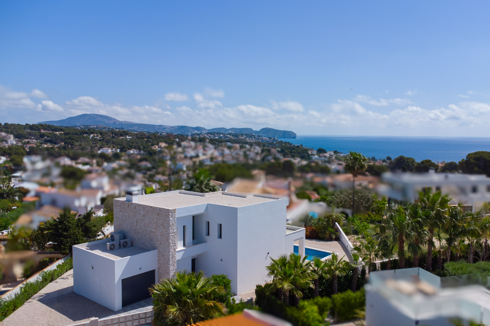 Elevated view of the modern villa featuring natural stone accents, a private pool, and expansive Mediterranean Sea views in Benissa.