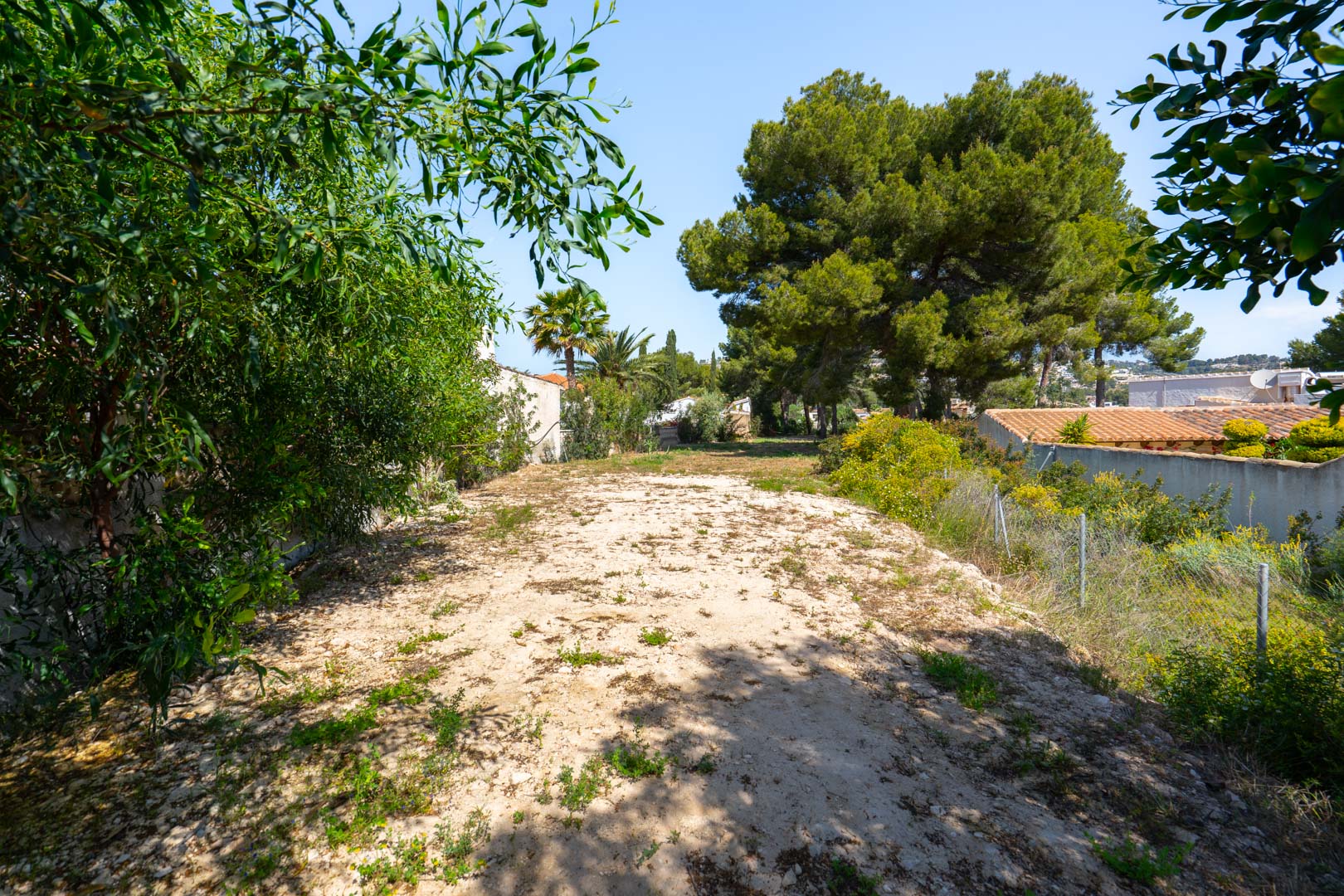 Expansive 900 m2 flat plot located behind the villa, bordered by mature trees and greenery, offering versatile space for guest houses or sports facilities.