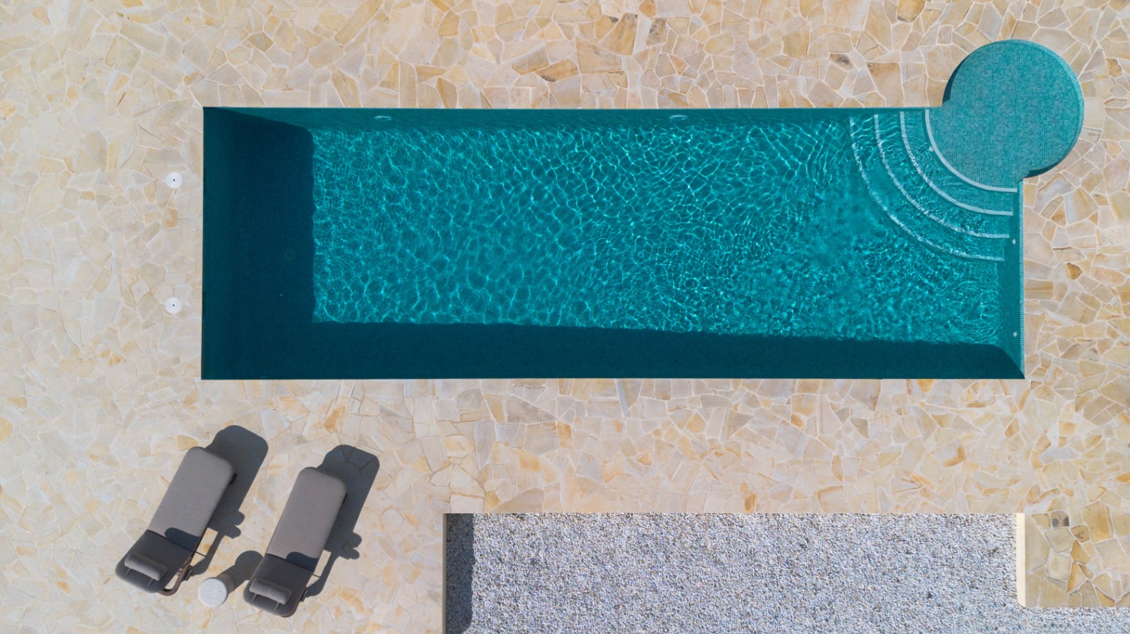 Aerial top-down view of the 13-meter rectangular pool featuring turquoise mosaic tiling, integrated circular steps, and a natural stone paved terrace.
