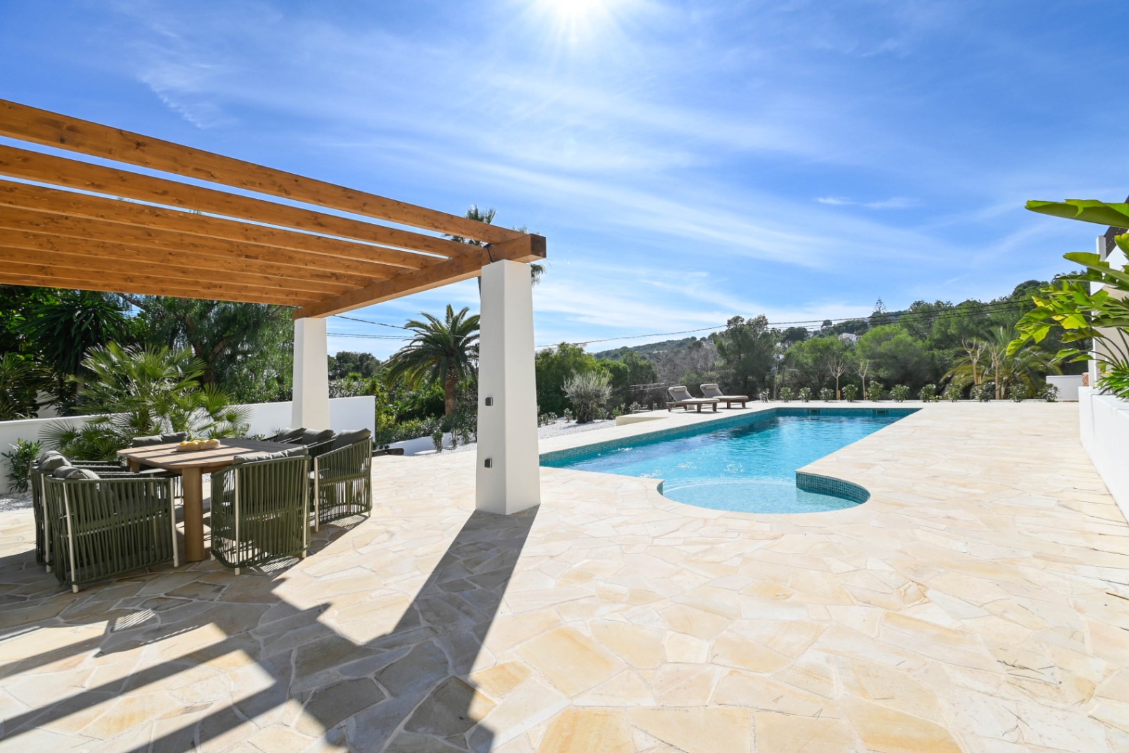 Outdoor terrace featuring natural stone paving, a wooden pergola with a dining area, and a 13-meter pool surrounded by Mediterranean landscaping.
