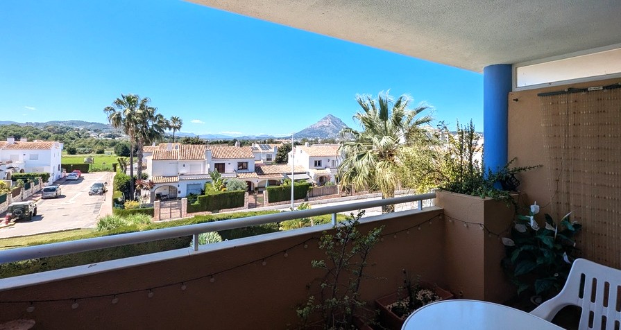 Private terrace featuring a metal railing and open views towards the Montgó mountain, overlooking local palm trees and Mediterranean architecture.