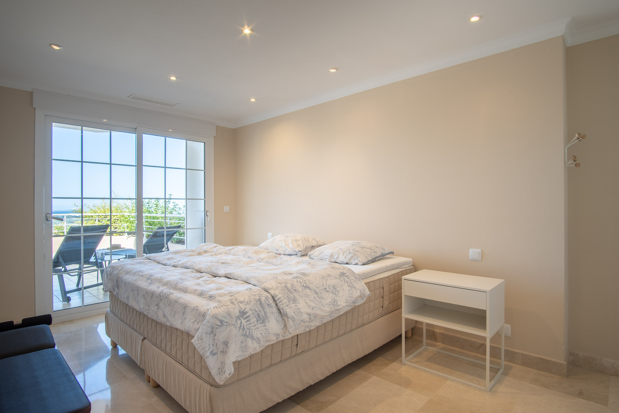 Bedroom featuring polished marble floors and recessed ceiling lighting. Large sliding glass doors provide direct access to the terrace and views of the Mediterranean landscape.