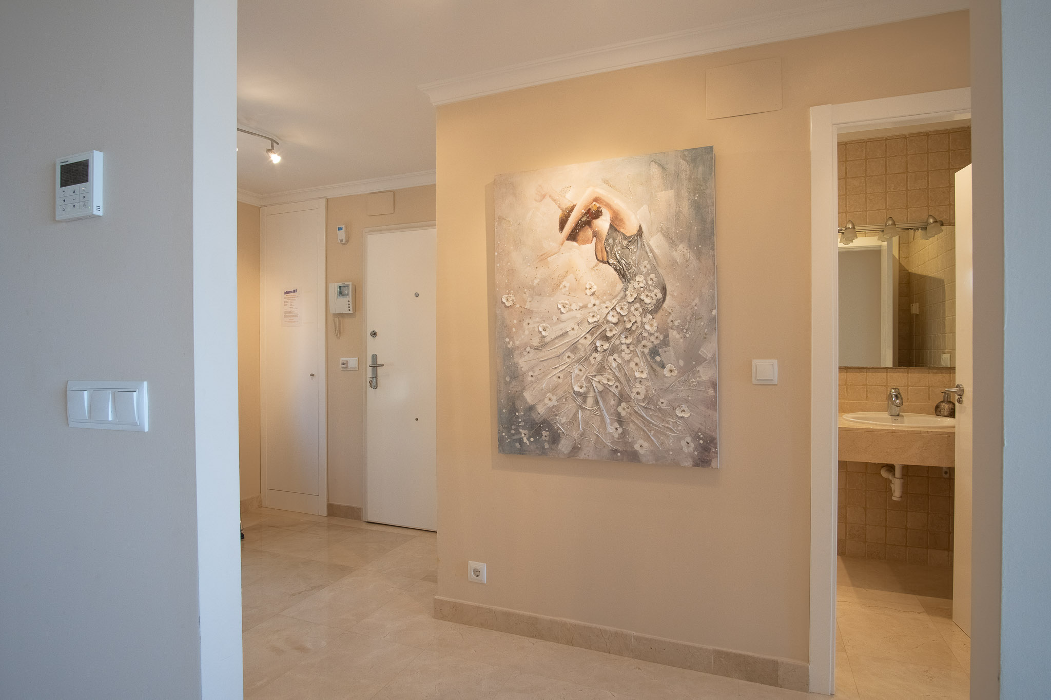 Entrance hall featuring marble flooring and white built-in storage, leading to a guest bathroom. Equipped with security intercom and climate control.