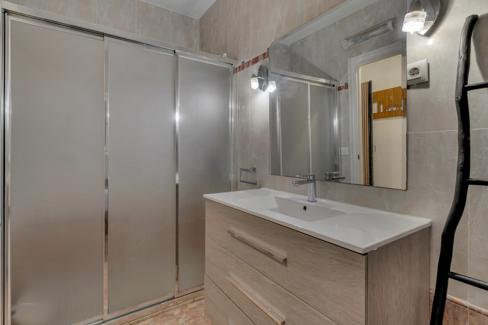 Bathroom detail featuring a sink embedded in a light wood vanity and a shower with sliding doors.