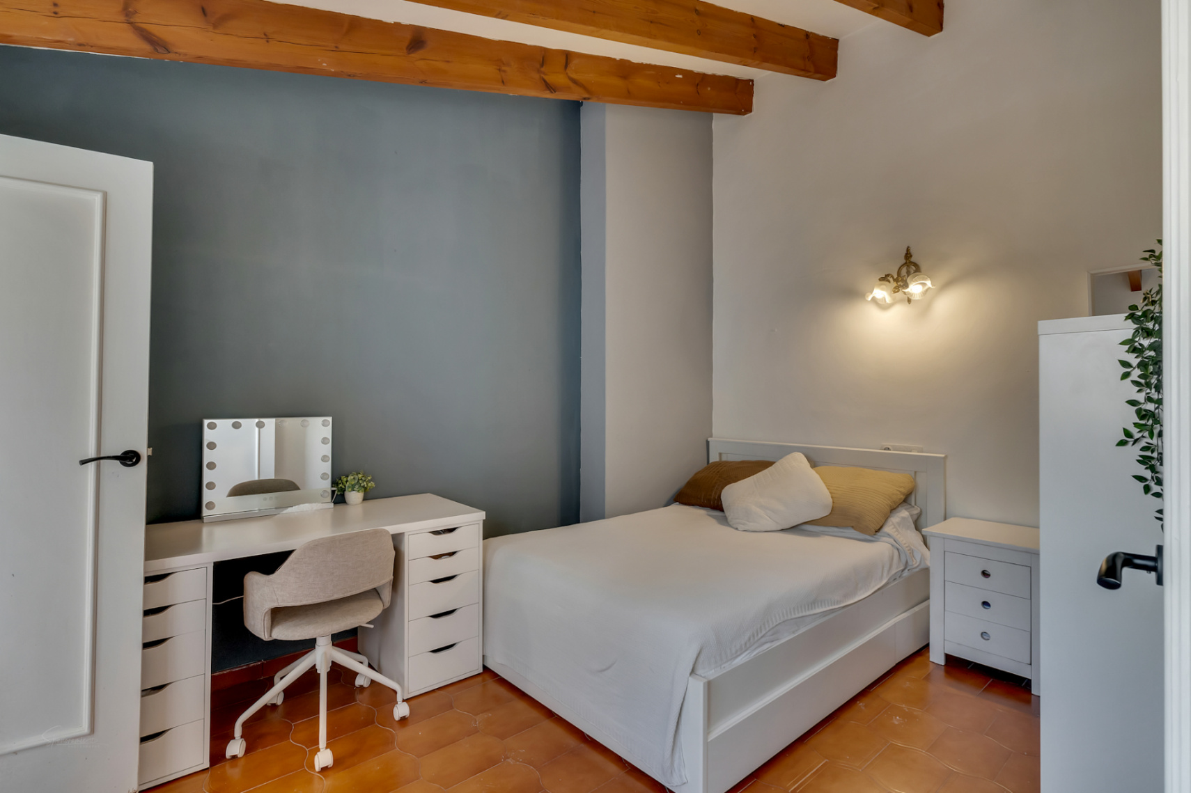 Bedroom featuring a white vanity desk and bed with white bedding.