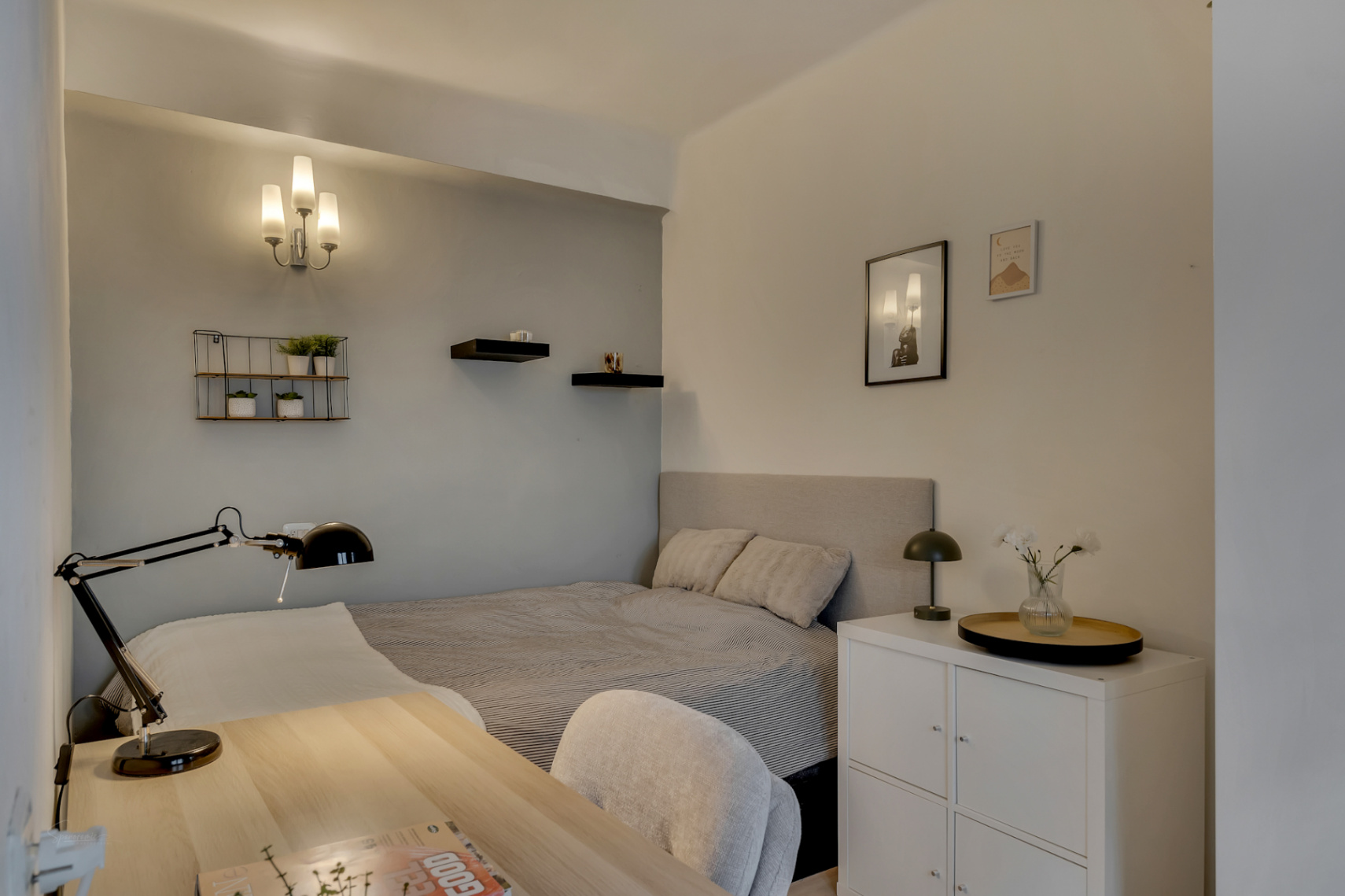 Bright bedroom featuring a light wood desk and decorative wall shelves.