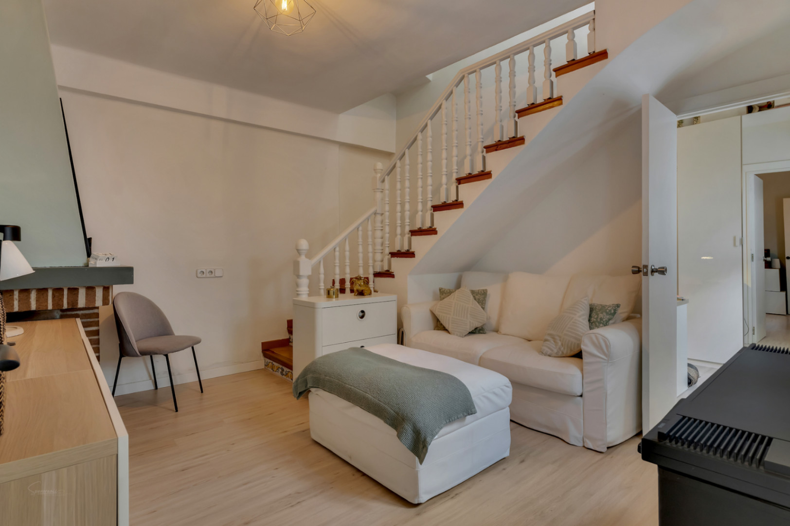 Bright living room with white wooden staircase and white sofa. Modern and minimalist decor.