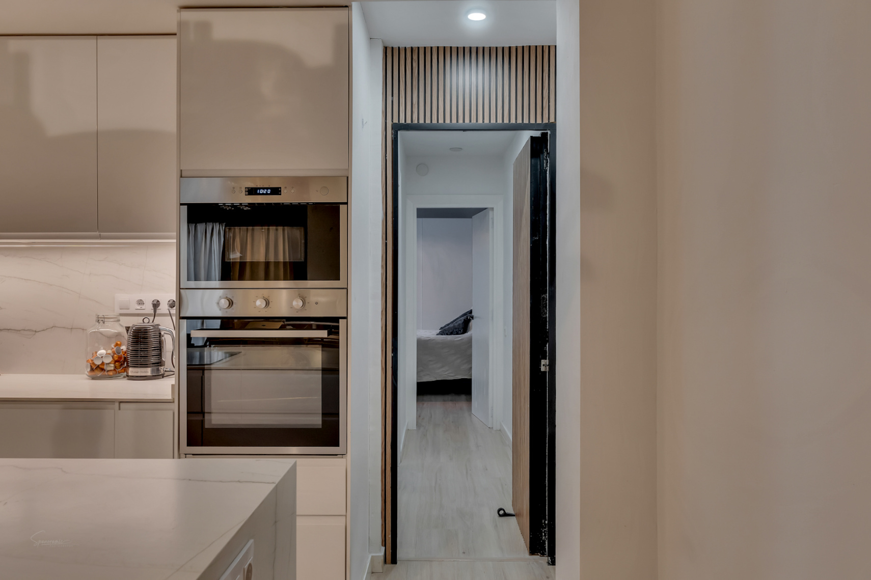 Kitchen detail with built-in oven and view of the bedroom through a doorway with wood design.