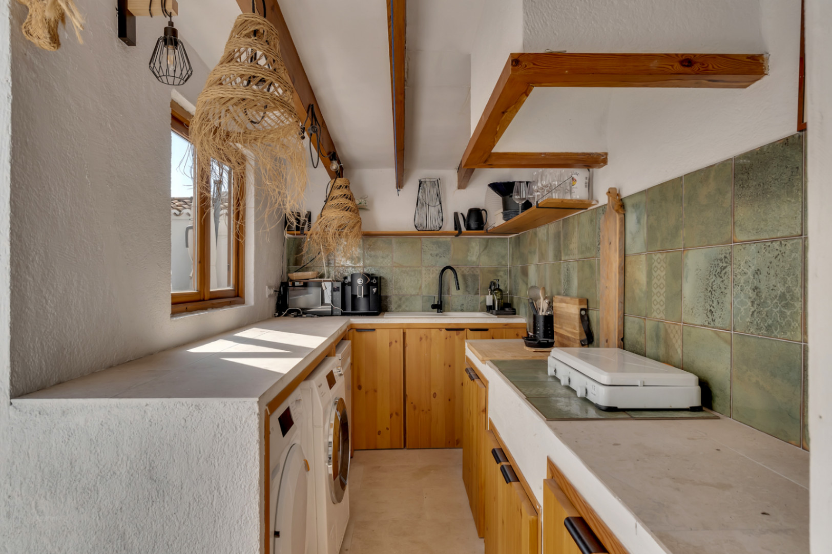 Kitchen detail with light wood cabinets, a built-in countertop, and green backsplash tiles.