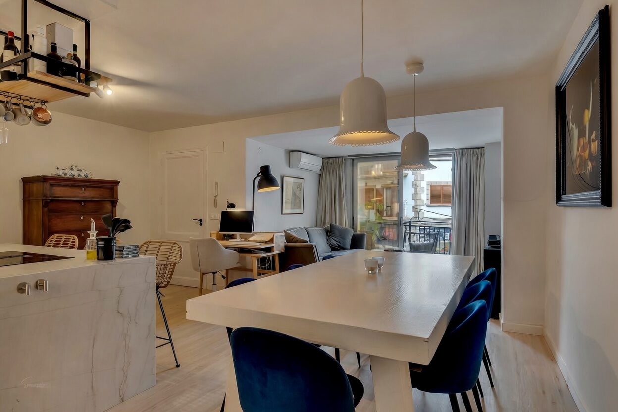 Living-dining area detail featuring a white table, blue velvet chairs, and terrace access.