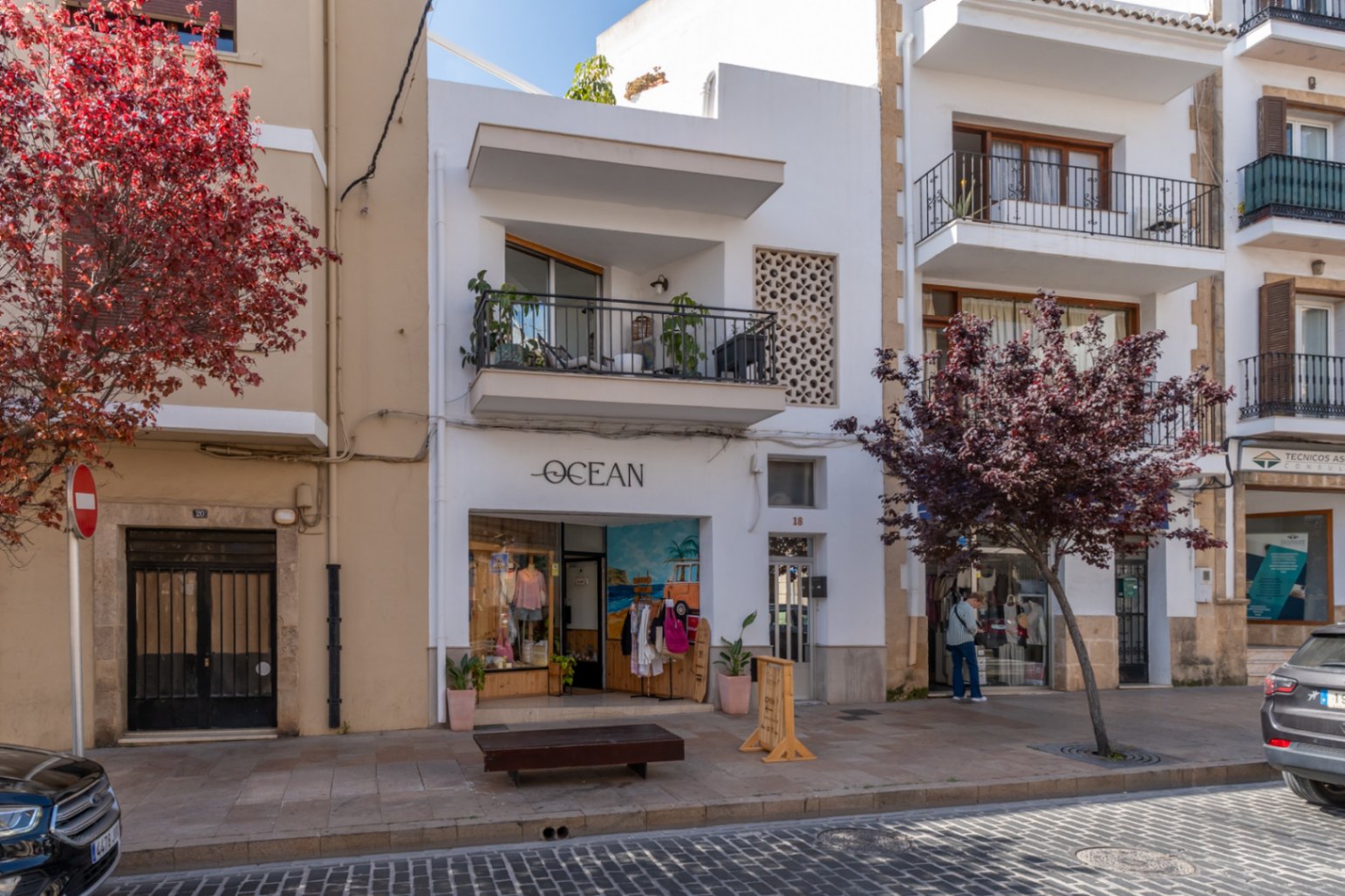 Renovated apartment building facade in the old town, featuring a balcony and a street-level shop.
