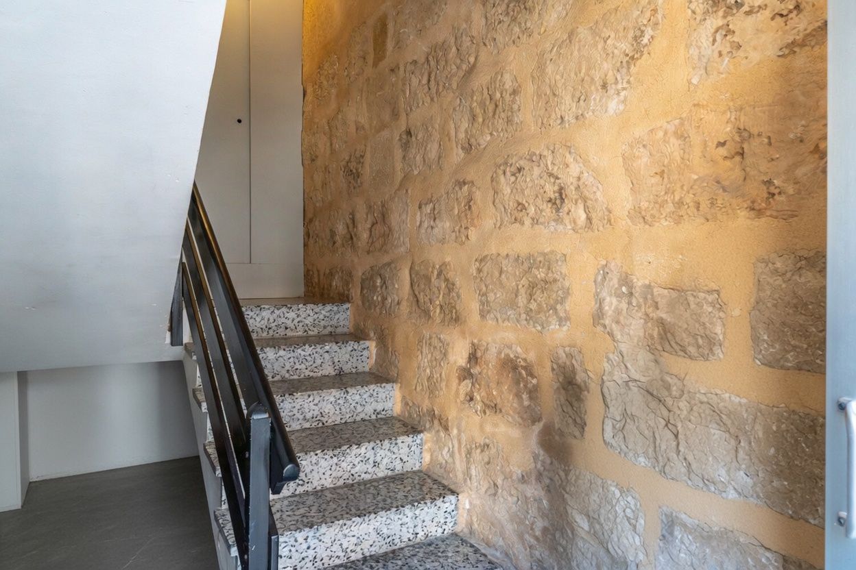 Staircase detail featuring an exposed stone wall and terrazzo steps.