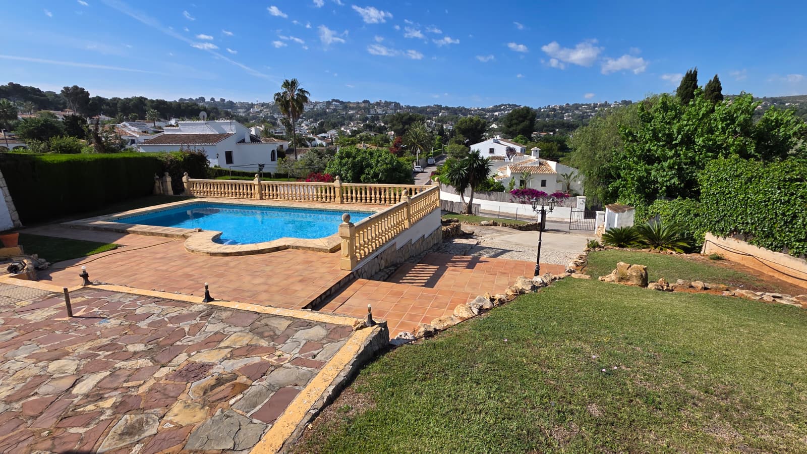 Outdoor swimming pool featuring a classic stone balustrade, terracotta sun terrace, and open views across the Tosalet neighborhood.