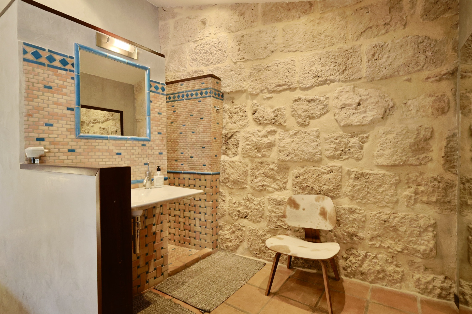 Bathroom detail with exposed stone wall and sink with decorative tiles.